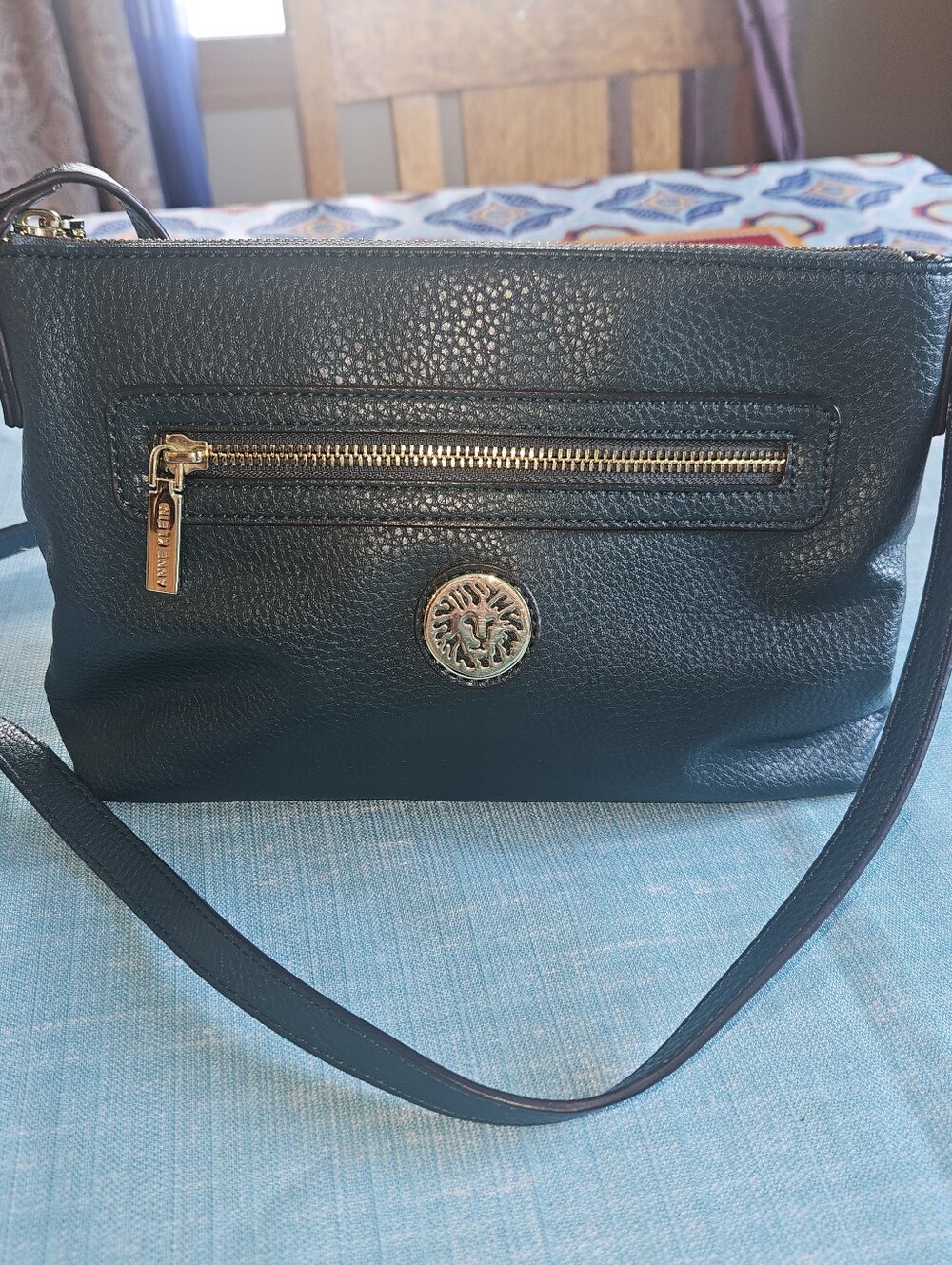 Anne Klein green crossbody bag with a gold lion logo.